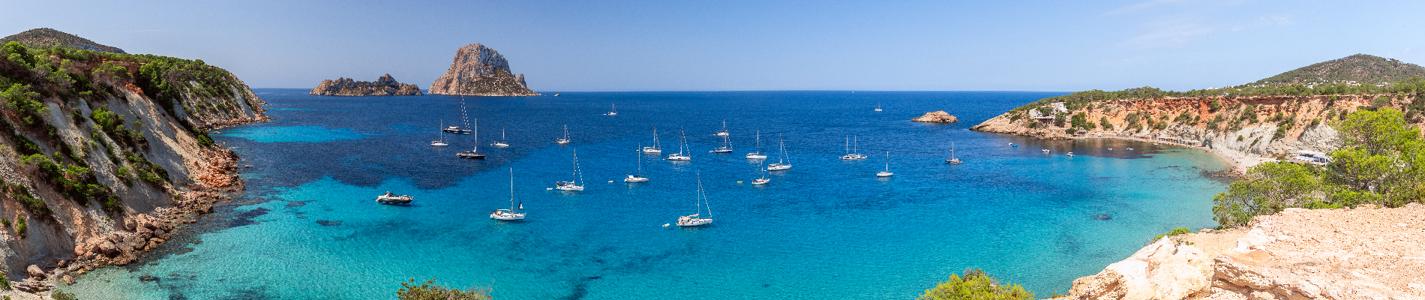 Hyper panorama of Cala Hort with sea sailing yachts and the mountain Es Vedra. Ibiza, Balearic Islands, Spain
