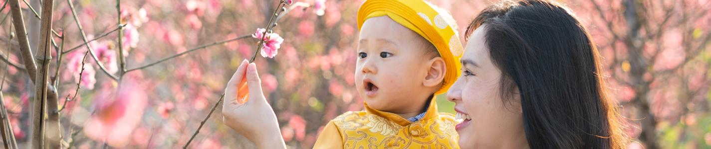 Young Vietnamese mother with her son in traditional costume in peach flower garden