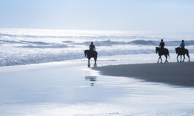 tourists exploring kuta beach bali at sunset on horseback