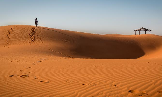  Alain, UAE. A man walking on the dunes early morning.