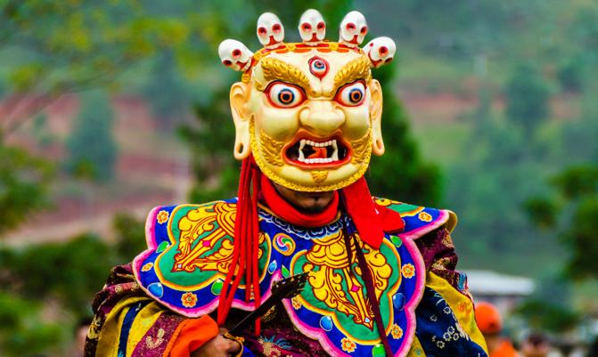 Bhutan, masked dancer at a traditional monastery festival the Wangdue Phodrang Tsechu. A monk in a colorful dress with mask during the tsechu (dance festival) in Wangdue, Bhutan.